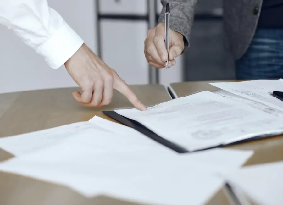 Dos personas revisando y firmando documentos notariales